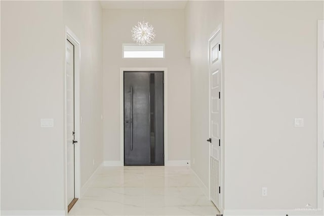 entryway with a chandelier, marble finish floor, and baseboards