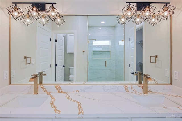 full bathroom with a stall shower, a notable chandelier, vanity, and toilet