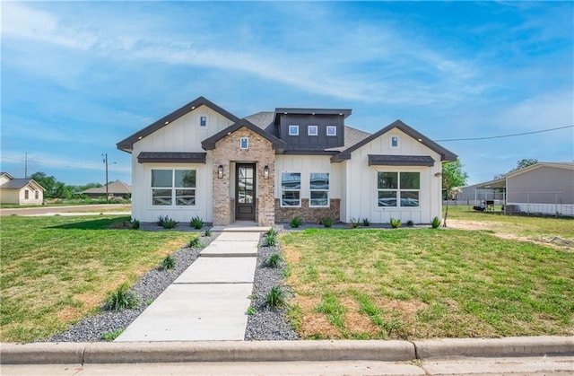 view of front of property featuring board and batten siding, a front lawn, and brick siding