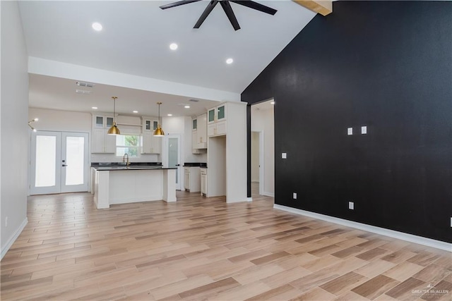 unfurnished living room featuring a sink, light wood finished floors, high vaulted ceiling, a ceiling fan, and visible vents