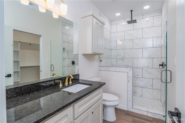 full bath with vanity, a stall shower, toilet, and wood finished floors
