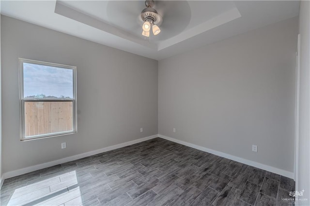 3021 Briggs Rd, Weslaco, TX 78596 - unfurnished room with a tray ceiling, baseboards, and dark wood-style floors