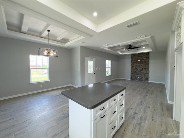 kitchen featuring a raised ceiling, white cabinetry, plenty of natural light, and ceiling fan with notable chandelier