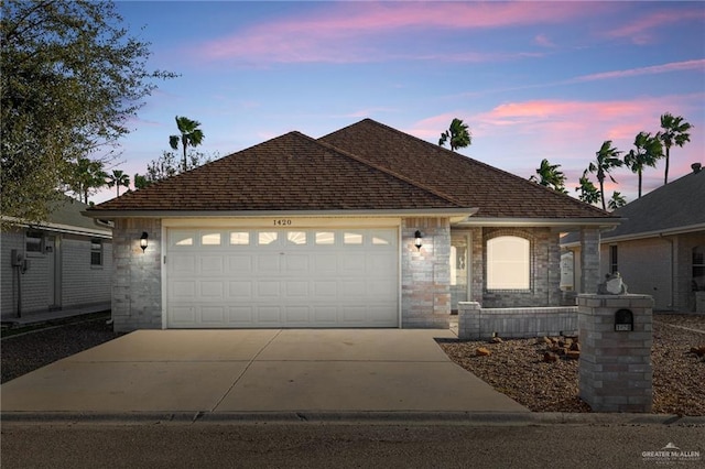 ranch-style house with driveway, stone siding, a shingled roof, and a garage