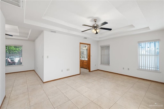 spare room featuring a tray ceiling, visible vents, and plenty of natural light