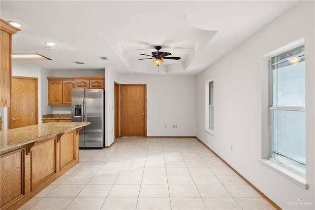 kitchen featuring light tile patterned flooring, visible vents, stainless steel refrigerator with ice dispenser, light stone countertops, and a tray ceiling