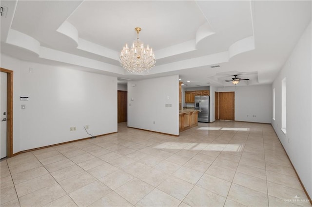 unfurnished living room featuring light tile patterned floors, baseboards, a tray ceiling, and ceiling fan with notable chandelier