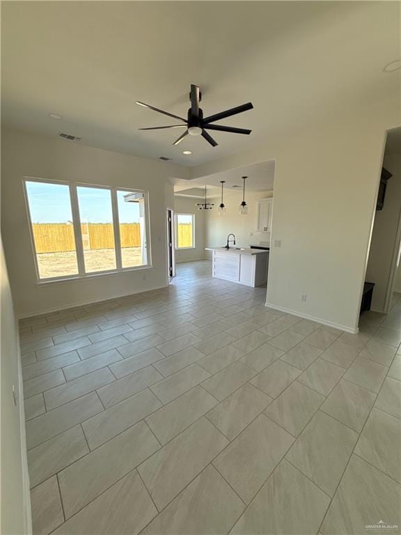 unfurnished living room with visible vents, baseboards, light tile patterned flooring, and a ceiling fan