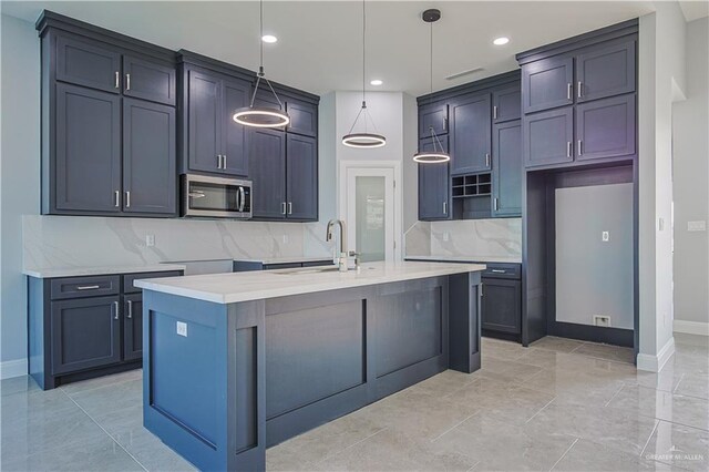 8043 N 50th St, Mcallen, TX 78504 - kitchen featuring decorative backsplash, baseboards, stainless steel microwave, a sink, and hanging light fixtures