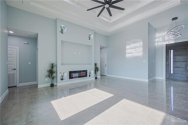 8043 N 50th St, Mcallen, TX 78504 - unfurnished living room with ceiling fan, a glass covered fireplace, baseboards, a towering ceiling, and a tray ceiling