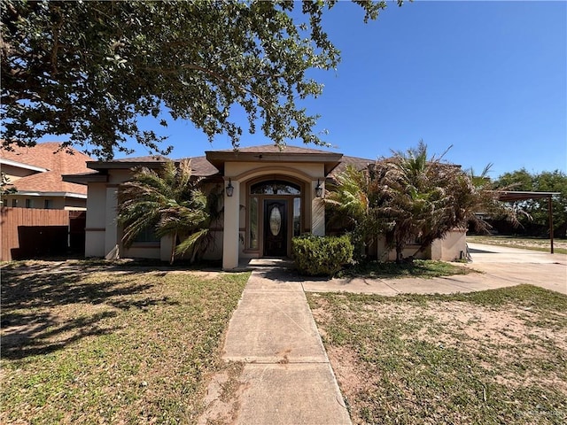 view of front of house with stucco siding, a front lawn, fence, and driveway