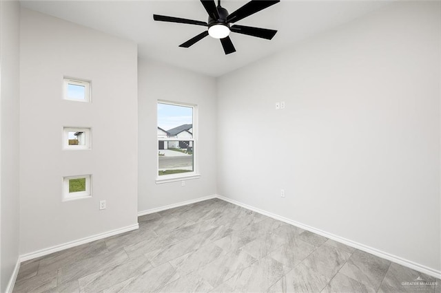 spare room featuring a ceiling fan and baseboards