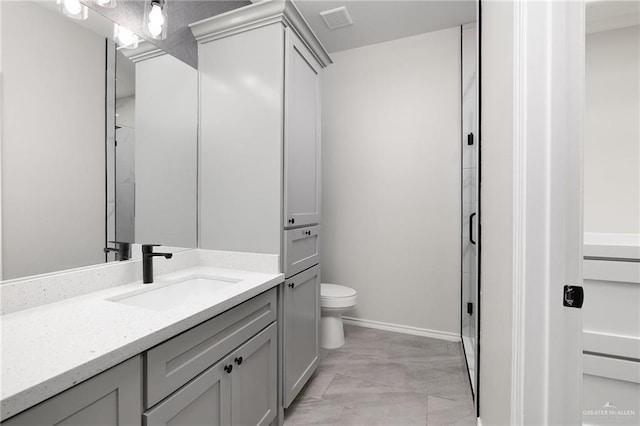 bathroom with a shower stall, toilet, vanity, and baseboards