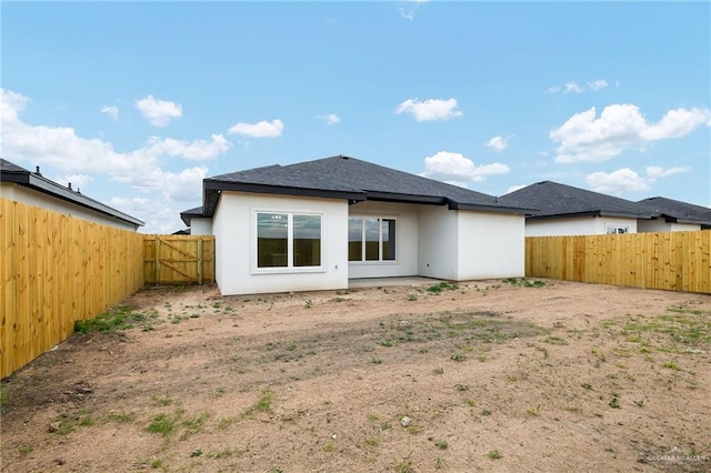 back of house featuring a fenced backyard and stucco siding