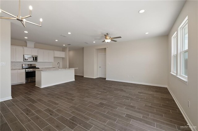 kitchen featuring stainless steel appliances, baseboards, open floor plan, and tasteful backsplash