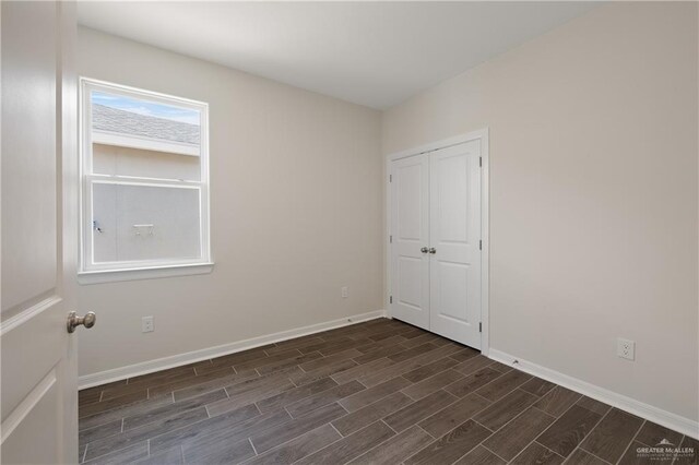 unfurnished room featuring baseboards and dark wood-style flooring