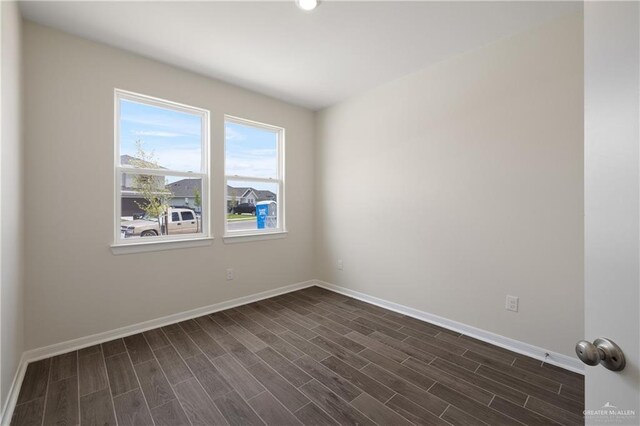 spare room featuring dark wood finished floors and baseboards