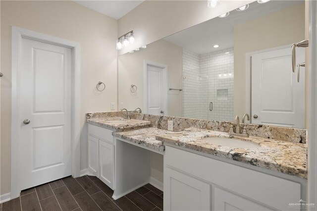 bathroom with wood tiled floor, double vanity, a stall shower, and a sink