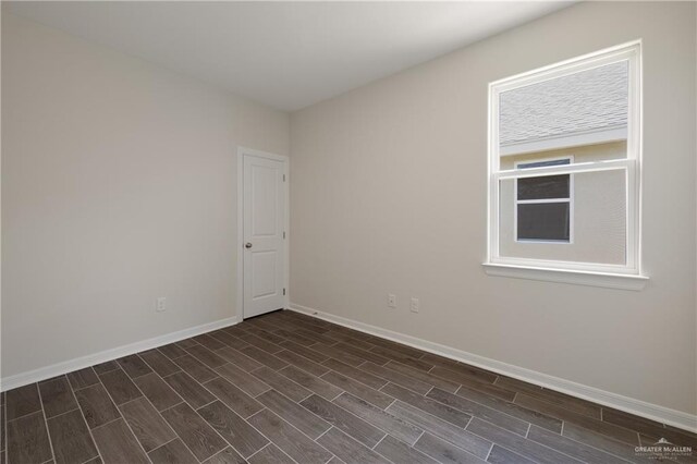 unfurnished room with baseboards and dark wood-style floors