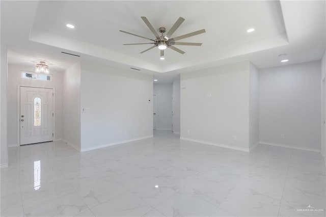 interior space with ceiling fan and a tray ceiling