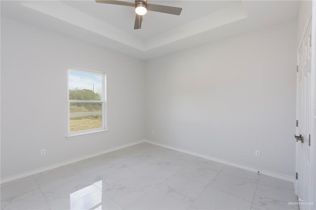 empty room featuring ceiling fan and a raised ceiling