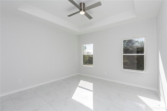 unfurnished room featuring ceiling fan and a raised ceiling