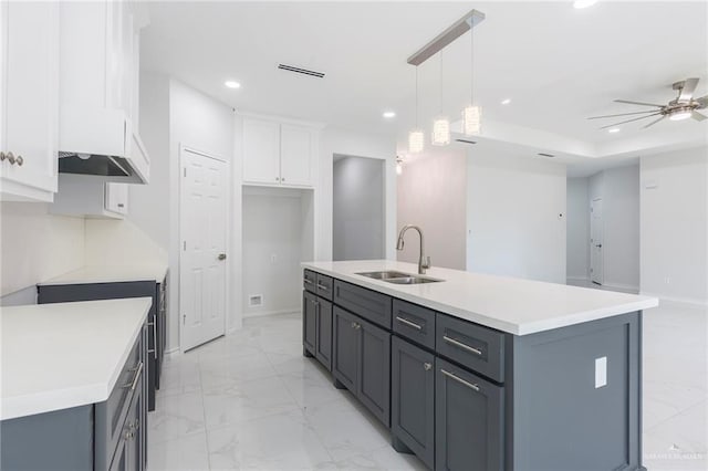 kitchen featuring decorative light fixtures, ceiling fan, a center island with sink, sink, and white cabinetry