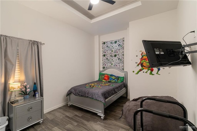 bedroom featuring dark wood-type flooring, ceiling fan, and a tray ceiling