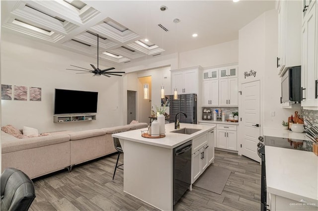 kitchen with white cabinets, dishwasher, coffered ceiling, and a center island with sink