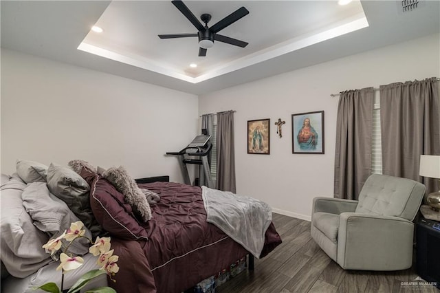 bedroom with a raised ceiling, ceiling fan, and dark wood-type flooring