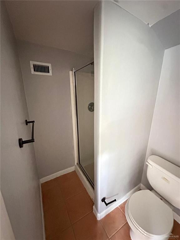 bathroom featuring toilet, a shower with door, and tile patterned flooring