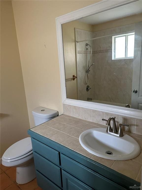 full bathroom featuring tiled shower / bath, vanity, and toilet