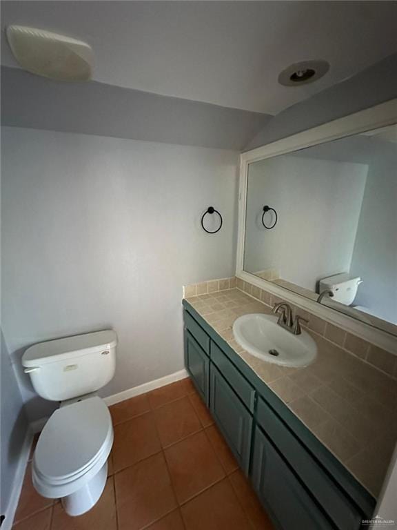 bathroom featuring tile patterned floors, vanity, toilet, and vaulted ceiling