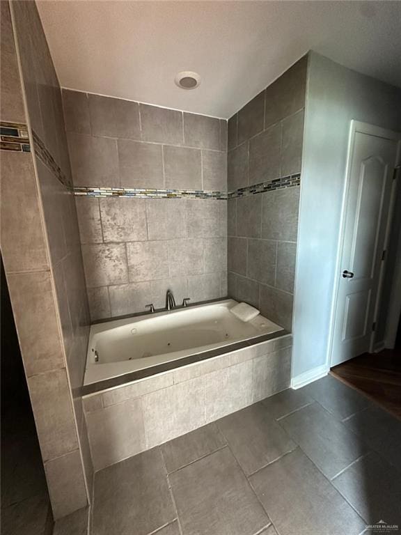 bathroom with a relaxing tiled tub and tile patterned flooring