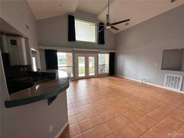 unfurnished living room featuring ceiling fan, sink, light tile patterned floors, and high vaulted ceiling