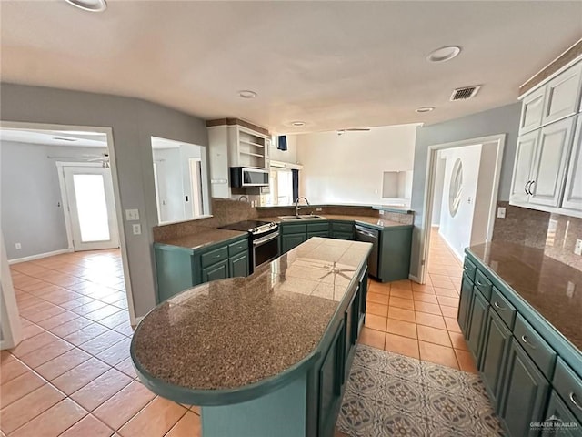 kitchen featuring light tile patterned flooring, sink, appliances with stainless steel finishes, kitchen peninsula, and decorative backsplash