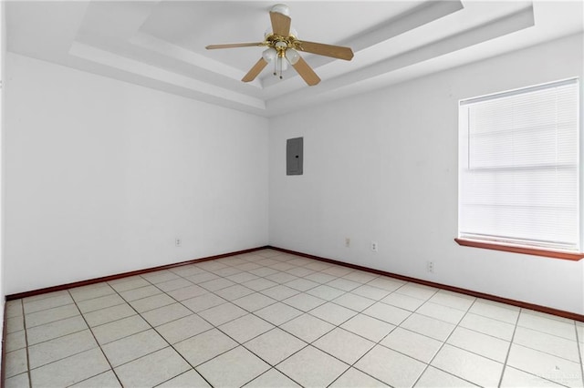 empty room with ceiling fan, a raised ceiling, light tile patterned floors, and electric panel