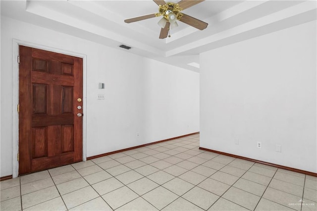 spare room with ceiling fan, light tile patterned flooring, and a tray ceiling