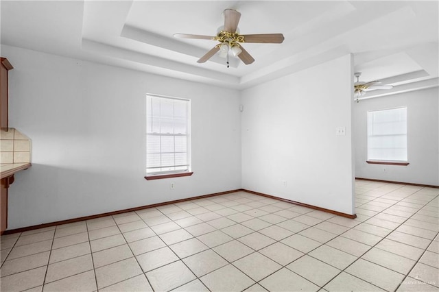 unfurnished room with light tile patterned floors, a raised ceiling, ceiling fan, and plenty of natural light