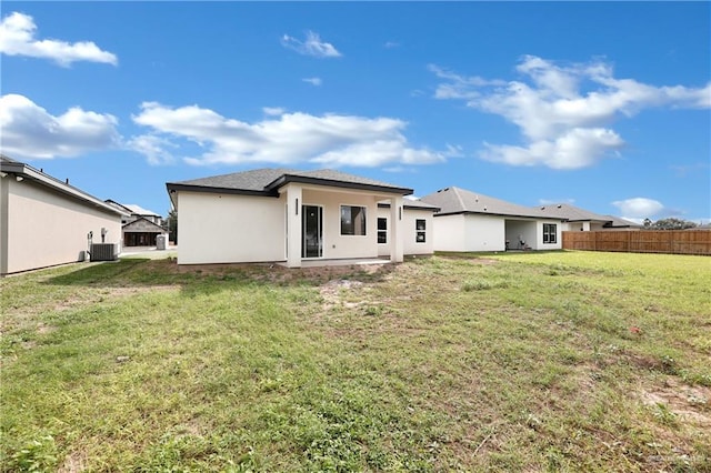 rear view of house with a yard, stucco siding, fence, and central AC unit