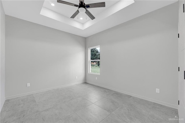 empty room with ceiling fan, a raised ceiling, baseboards, and recessed lighting