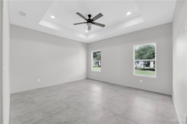 spare room with a tray ceiling, plenty of natural light, a ceiling fan, and recessed lighting