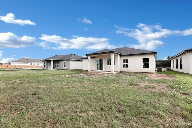 back of house featuring a lawn, cooling unit, and stucco siding