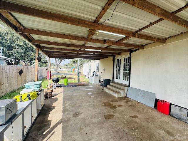 view of patio featuring entry steps, an attached carport, a trampoline, fence, and french doors