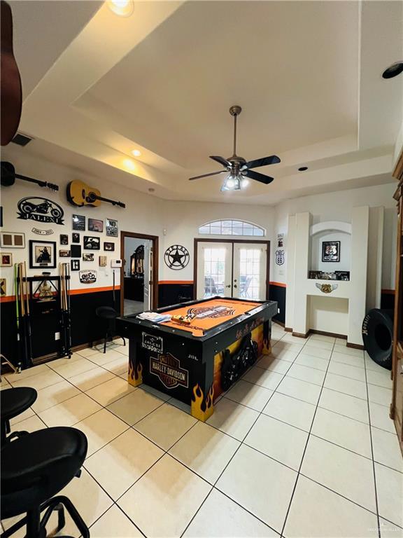 playroom featuring light tile patterned floors, a tray ceiling, ceiling fan, and french doors