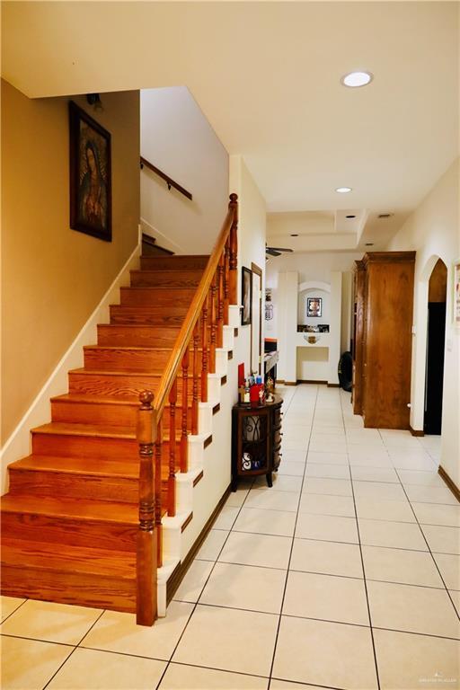 stairway featuring tile patterned flooring, recessed lighting, arched walkways, and baseboards