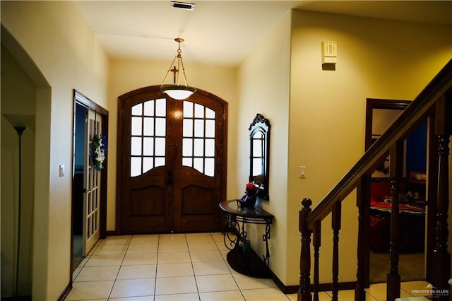 foyer featuring visible vents, stairs, french doors, light tile patterned flooring, and arched walkways