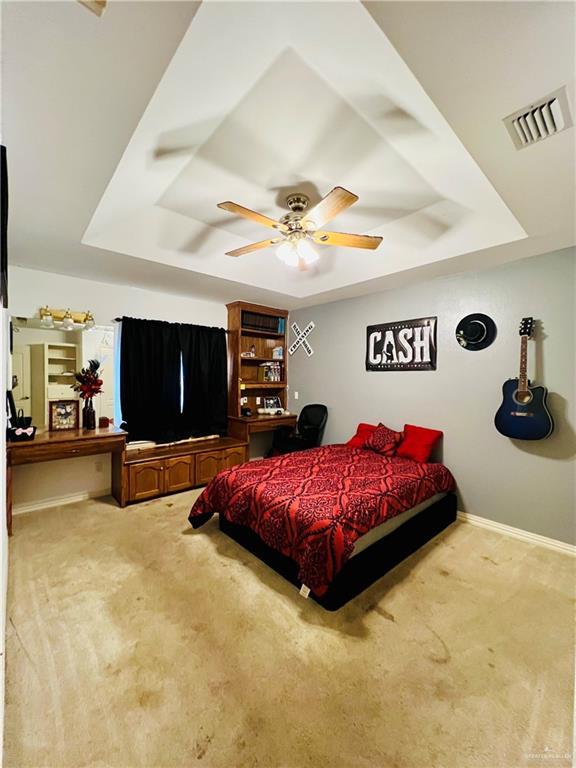 bedroom featuring a tray ceiling, visible vents, and carpet flooring