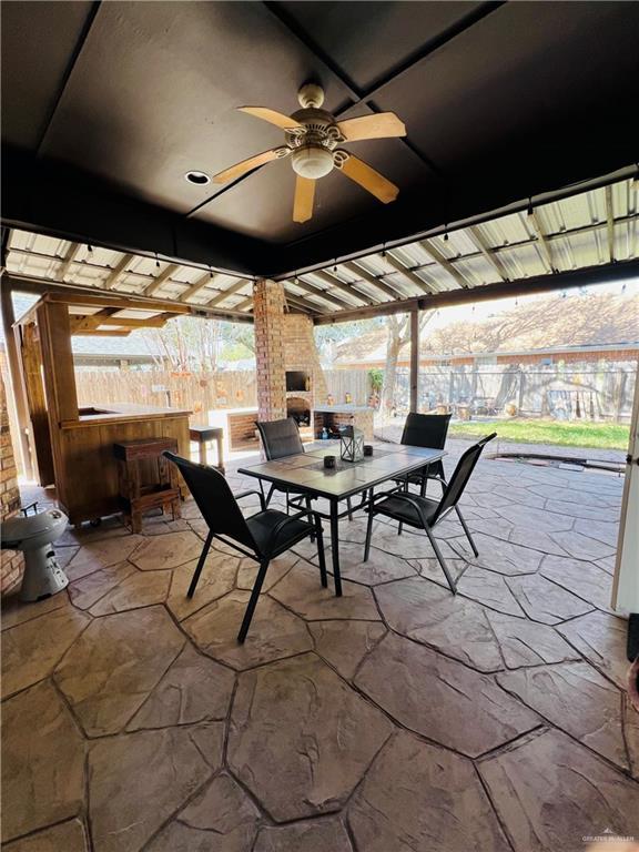 view of patio with outdoor dining space, ceiling fan, a fireplace, and a fenced backyard