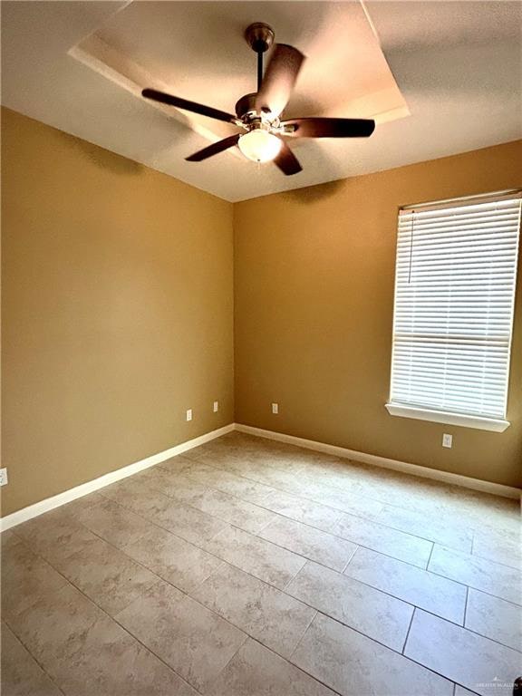 unfurnished room featuring a raised ceiling and ceiling fan